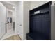 A mudroom with a dark blue organizer featuring hooks and storage, leading to a laundry area at 129 Alumroot Rd, Holly Springs, NC 27540