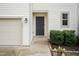Inviting front door, complemented by manicured shrubs, a garage door, and an outdoor lantern at 157 Lynn Dr, Clayton, NC 27520