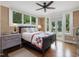 Bright bedroom featuring hardwood floors, ceiling fan, and large windows overlooking the outdoor landscape at 1624 Hopkins Rd, Bahama, NC 27503