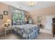 Bright bedroom featuring a large window, curtains, a bed with blue accents, and neutral walls at 1624 Hopkins Rd, Bahama, NC 27503