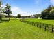 Expansive green pasture with fencing, a horse shelter, and a country estate in the distance at 1624 Hopkins Rd, Bahama, NC 27503