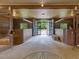 Inside horse stables with open stalls, rubber floor and an opening with black framed french doors to the outside at 1624 Hopkins Rd, Bahama, NC 27503