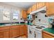 Functional kitchen featuring wooden cabinetry, white appliances, and tiled backsplash at 1624 Hopkins Rd, Bahama, NC 27503