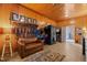 Wood paneled tack room featuring a sofa, saddles, and bridle racks for organized storage at 1624 Hopkins Rd, Bahama, NC 27503