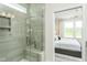 Modern tiled walk-in shower with glass door adjacent to bedroom with plush bedding at 1816 Gazania Dr, Fuquay Varina, NC 27526