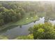 Aerial view showcasing lush green golf course with serene pond and mature trees at 1925 Hunting Ridge Rd, Raleigh, NC 27615