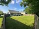 Large, grassy backyard with a wooden fence and partial view of neighboring houses at 201 Joe Gibson Dr, Gibsonville, NC 27249