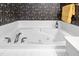 Close-up of a pristine white bathtub with gold fixtures and designer wallpaper at 2012 Muirfield Ct, Elon, NC 27244