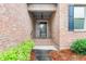 Inviting brick home featuring covered front porch, mature landscaping, and blue shutters on front window at 2012 Muirfield Ct, Elon, NC 27244