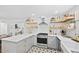 Well-lit kitchen featuring gray cabinetry, quartz countertops, modern appliances, and decorative floating shelves at 218 Lafayette Rd, Raleigh, NC 27604