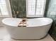 Bright bathroom showcasing a sleek white standalone tub with a wooden tray and window at 2212 Oxford Hills Dr, Raleigh, NC 27608