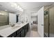Bright bathroom features a double vanity with black cabinets, large mirror, and tiled shower at 2412 Averon Dr, Fuquay Varina, NC 27526