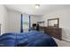 This bedroom includes a bed with blue covers, a study desk, and a view of the neighborhood at 2412 Averon Dr, Fuquay Varina, NC 27526