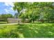 Expansive backyard featuring lush greenery, mature trees, a large garage, and a play structure at 250 Dixon Rd, Graham, NC 27253