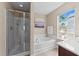 Bright bathroom with a glass-enclosed shower, soaking tub, and a large window overlooking the backyard at 2821 Corbett Grove Dr, Raleigh, NC 27604