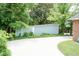 Spacious backyard with a storage shed and mature trees, and a large, paved area at 303 Spring St, Louisburg, NC 27549