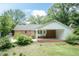 Backyard view featuring a covered patio, lush greenery, and detached garage at 303 Spring St, Louisburg, NC 27549