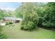 Lush backyard with mature trees and the house in the background; beautiful outdoor space at 303 Spring St, Louisburg, NC 27549