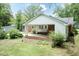 Backyard view featuring a covered patio, lush greenery, and detached garage at 303 Spring St, Louisburg, NC 27549