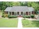 Charming brick home featuring a well-manicured front lawn and an inviting covered porch at 303 Spring St, Louisburg, NC 27549