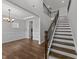 Bright foyer featuring wood floors, elegant lighting, a staircase with wood and iron railing, and wainscoting at 3500 Bailey Lake Dr, Fuquay Varina, NC 27526