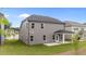 View of the back of the two-story home with gray siding, windows, a covered patio, and a large lawn at 3500 Bailey Lake Dr, Fuquay Varina, NC 27526
