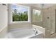 Modern bathroom with a soaking tub, separate tiled shower, and views of nature at 359 Abbot Pl, Chapel Hill, NC 27516