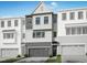 View of newly constructed townhomes featuring vertical siding, dormer and attached two car garages at 4713 Mint Leaf Ln, Raleigh, NC 27612