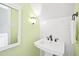 Bright half bathroom with a pedestal sink, classic fixtures, and modern green and white wall tiling at 4720 Cedarfield Dr, Raleigh, NC 27606