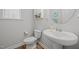 Cozy half bathroom featuring wood floors, a pedestal sink, and decorative wall hangings at 525 Marion Hills Way, Knightdale, NC 27545