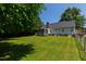 Wide backyard view of home exterior featuring large lawn, screened porch, and chain link fence at 5413 Lower Creek Ct, Apex, NC 27539