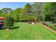 Expansive backyard featuring a meticulously maintained lawn, mature trees, and play area at 6004 Brass Tack Ct, Fuquay Varina, NC 27526