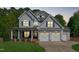 Charming two-story home at twilight, featuring a three-car garage, inviting front porch, and manicured lawn at 6004 Brass Tack Ct, Fuquay Varina, NC 27526
