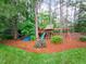 Wooden play set with slides and swings, surrounded by natural mulch for safety and fun at 6004 Brass Tack Ct, Fuquay Varina, NC 27526