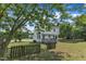Two-story white house with a wooden fence, deck, and grass lawn in a tree filled backyard at 6221 Winter Spring Dr, Wake Forest, NC 27587