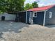 Rear exterior view of the house with gravel, fence, air conditioner and red metal roof at 713 Champion St, Henderson, NC 27536