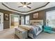 Bedroom boasts a tray ceiling, ceiling fan, bedside tables, a reading bench, and doorway to the bathroom at 732 Keystone Park Dr, Morrisville, NC 27560