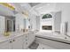 Bright bathroom featuring double sinks, vanity, large window and a soaking tub at 7605 Pats Branch Dr, Raleigh, NC 27612