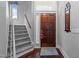 Inviting entryway featuring hardwood floors, carpeted stairs, and wooden front door at 7605 Pats Branch Dr, Raleigh, NC 27612