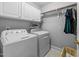 Functional laundry room with white washer, dryer, upper cabinets, and clothing rack at 7605 Pats Branch Dr, Raleigh, NC 27612
