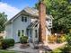 Exterior rear of home with a tall brick chimney, brick patio with outdoor seating and landscaping at 7605 Pats Branch Dr, Raleigh, NC 27612