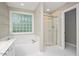 Bright bathroom featuring a window with glass blocks, soaking tub, and glass enclosed shower at 904 Oldwyck Dr, Fuquay Varina, NC 27526
