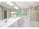 Bright bathroom with dual sinks, large mirror, glass block window, soaking tub, and walk-in shower at 904 Oldwyck Dr, Fuquay Varina, NC 27526