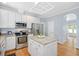 Well-lit kitchen with stainless steel appliances, granite countertops, white cabinets and a center island with room for seating at 904 Oldwyck Dr, Fuquay Varina, NC 27526
