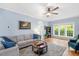 Comfortable living room with hardwood floors, a large sofa, windows, a ceiling fan, and a bookshelf at 904 Oldwyck Dr, Fuquay Varina, NC 27526