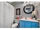 Stylish bathroom featuring patterned wallpaper, a blue vanity, and a round mirror at 908 Town Side Dr, Apex, NC 27502