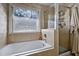 Bright bathroom featuring a bathtub under a window and a glass shower at 908 Town Side Dr, Apex, NC 27502