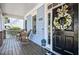 Cozy front porch with wicker rocking chairs and a charming wreath on the front door at 908 Town Side Dr, Apex, NC 27502