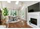Sunlit breakfast area with a fireplace, hardwood floors, large windows, and an elegant chandelier at 9136 Palm Bay Cir, Raleigh, NC 27617