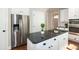 Kitchen with stainless steel refrigerator, white cabinetry, black granite counters, and a central island cooktop at 9136 Palm Bay Cir, Raleigh, NC 27617